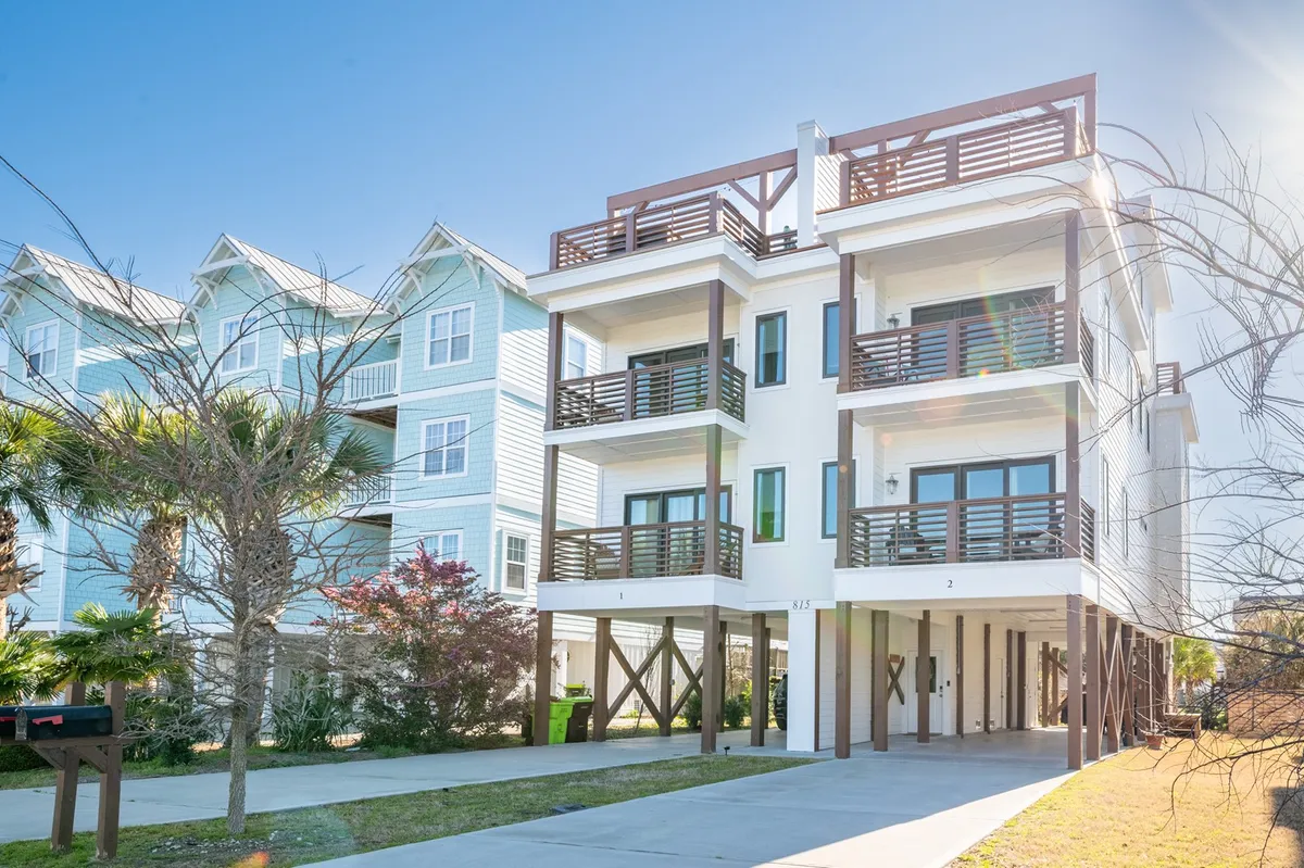 The exterior of a multi-level home features well-appointed balconies and attractive landscaping, basking in soft natural light. The inviting balconies suggest spaces for relaxation and sunset viewing after a day of activities.