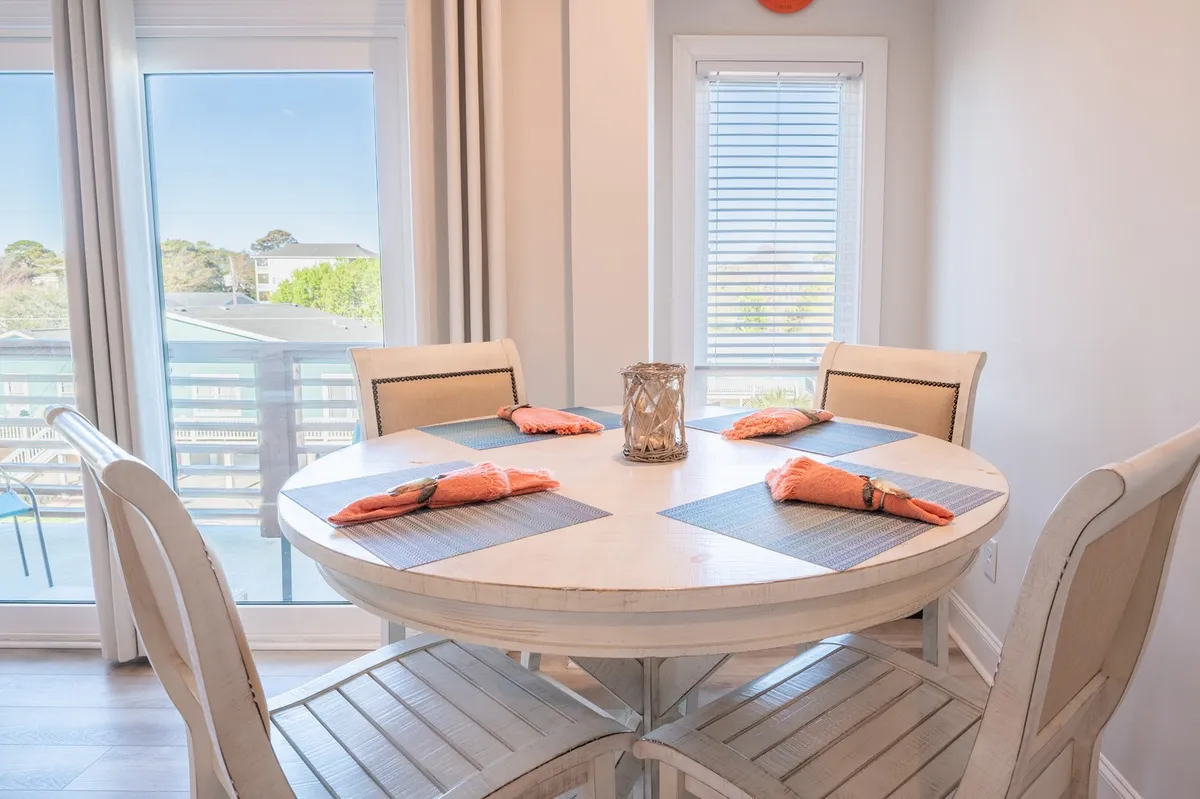 A cozy dining area with a round table set for a meal, decorative napkins, a centerpiece lantern, and large windows drawing in natural light. The scene is welcoming and perfect for both family dinners and group celebrations, matching the narrative's focus on lively dining experiences.