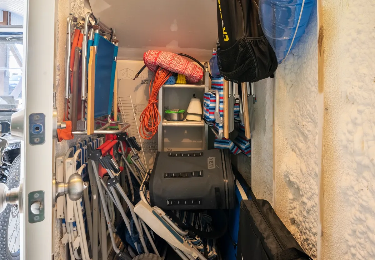 A practical storage area filled with folding chairs, colorful cushions, and beach gear such as bags and ropes. The image conveys readiness for outdoor adventure and the convenience of having everything organized and accessible.