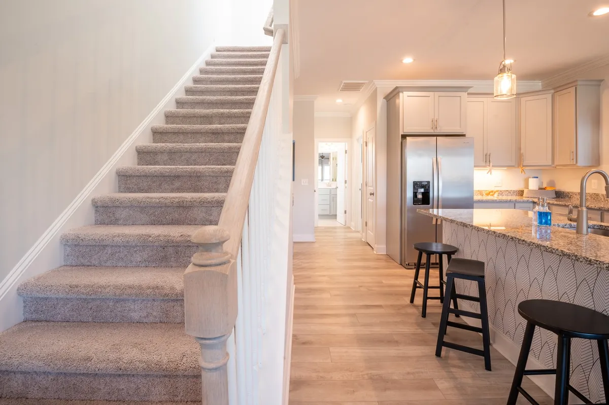 A modern kitchen with a large island and bar stools sits ready for shared meals or casual entertaining. The inviting space is ideal for celebrating holidays, preparing for market days, or gathering with friends and family during any season.