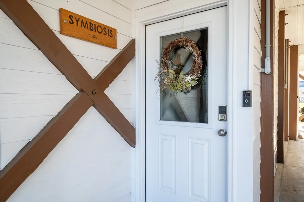 A welcoming entryway with a decorative wreath on the door and a wooden sign reading 'SYMBIOSIS.' The entrance feels festive and inviting, setting the tone for group arrivals and meaningful gatherings.