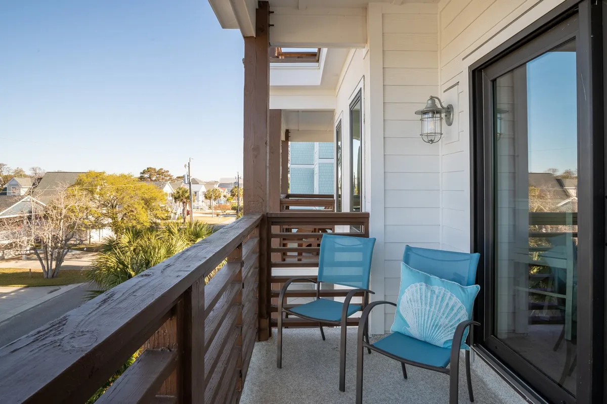 An inviting balcony setup with blue chairs, a shell-shaped pillow, and a sturdy railing. The perspective highlights comfort and relaxation, ideal for enjoying sunrise or evening gatherings after outdoor excursions.